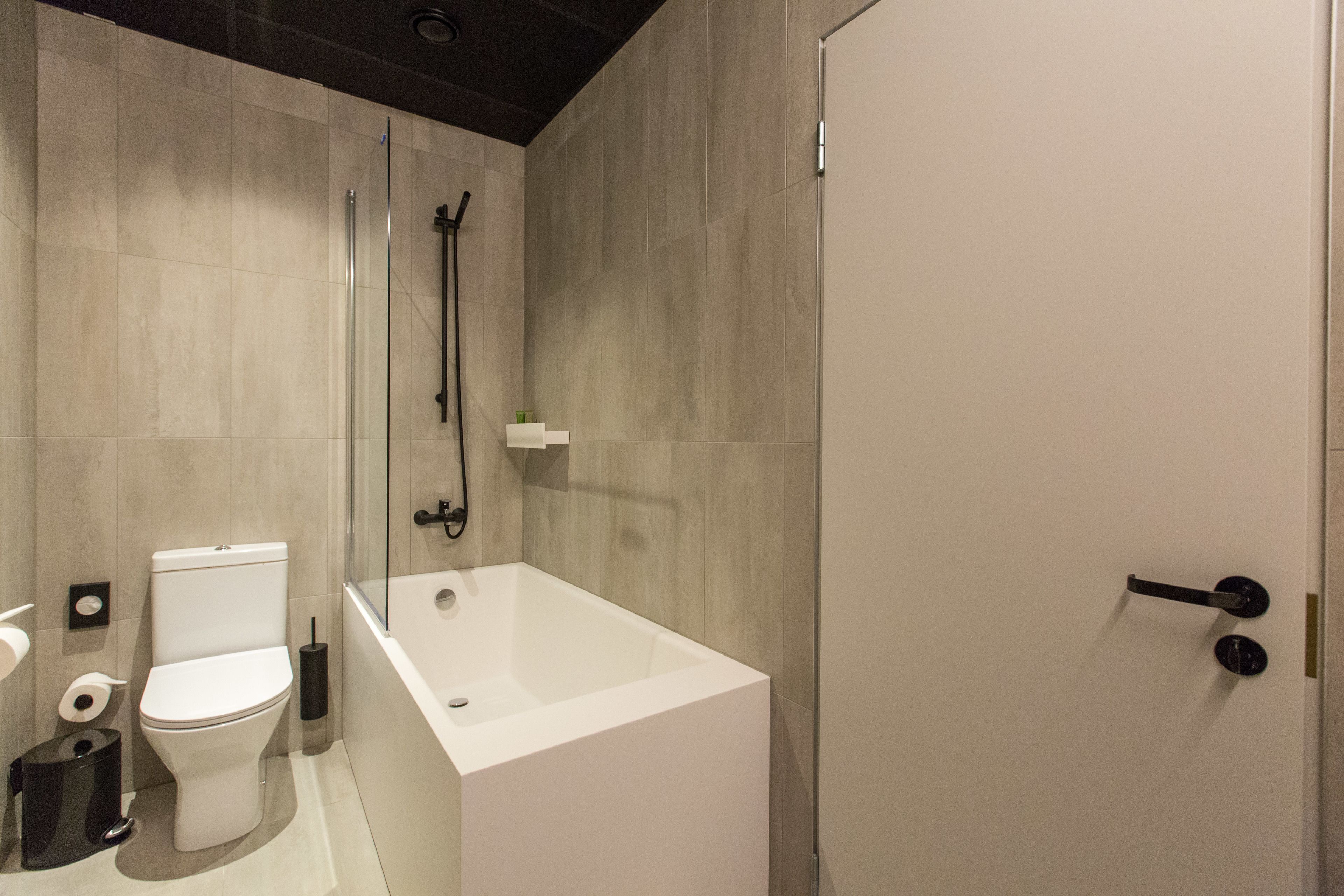 A modern bathroom with a white toilet, a bathtub, and a glass-enclosed shower.