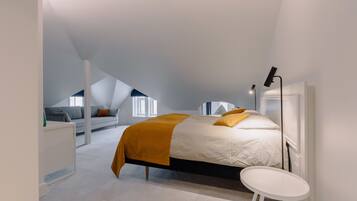 A modern bedroom with a bed, a small white table, and a desk.