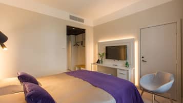 Ein modernes Hotelzimmer mit Bett, Schreibtisch, Stuhl und Fernseher.