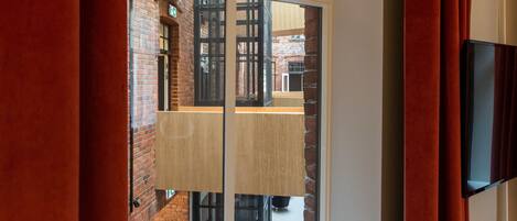 Una habitación con un amplio ventanal, un banco blanco y un televisor de pantalla plana montado en la pared.