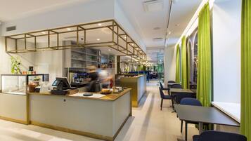 A modern cafe with a counter, seating area, and a visible kitchen.