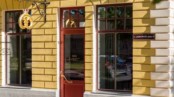 A yellow building with a red door and large windows. A sign on the building reads "J. Laidoneri plats 8".