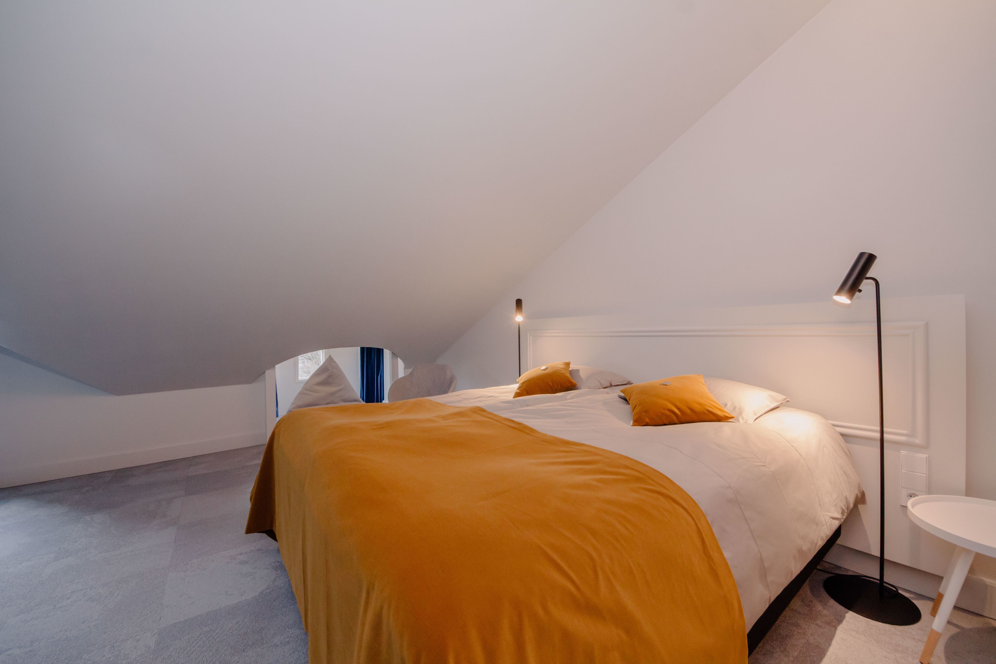 Une chambre à coucher avec un lit, une table de chevet et une lampe sur pied.