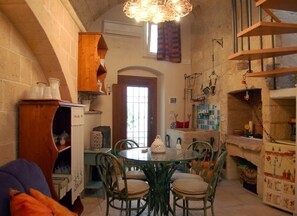 A cozy dining area with a round table and chairs, a wooden cabinet, and a decorative ceiling light. - Letto e Merenda (Nardò)