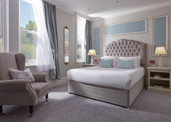 A bedroom with a large bed, a chair, a nightstand, a mirror, and a window with curtains. - Bathen House Boutique Hotel (Bath)
