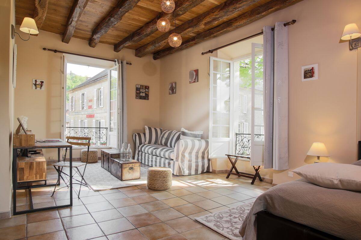 Ein gemütliches Zimmer mit einem Bett, einer gestreiften Couch, einem Esstisch und einer Küchenzeile.