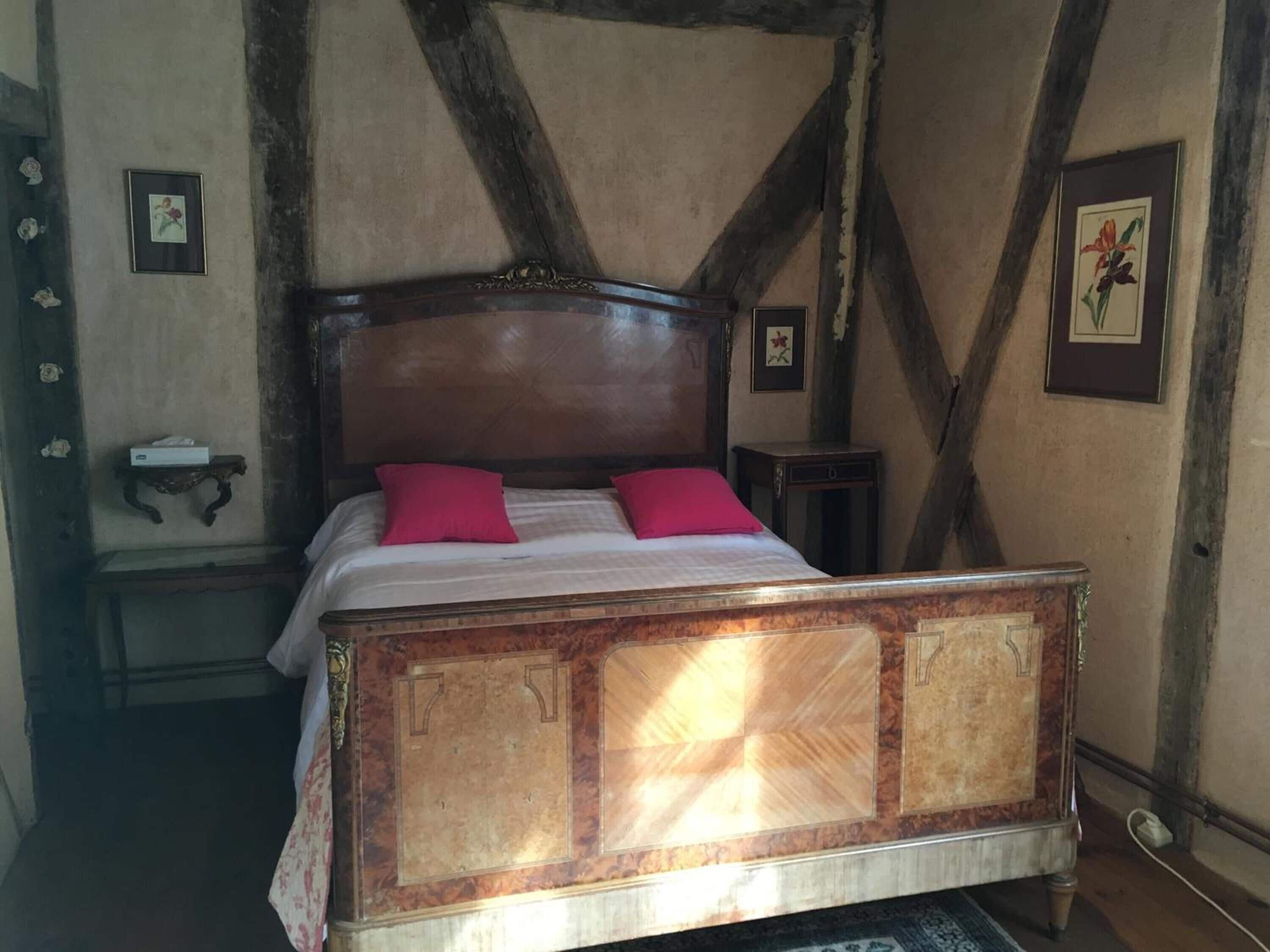 A traditional bedroom with a wooden four-poster bed, a nightstand, and a small table.