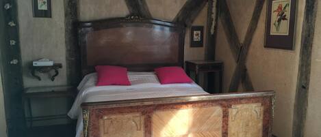 A traditional bedroom with a wooden four-poster bed, a nightstand, and a small table.