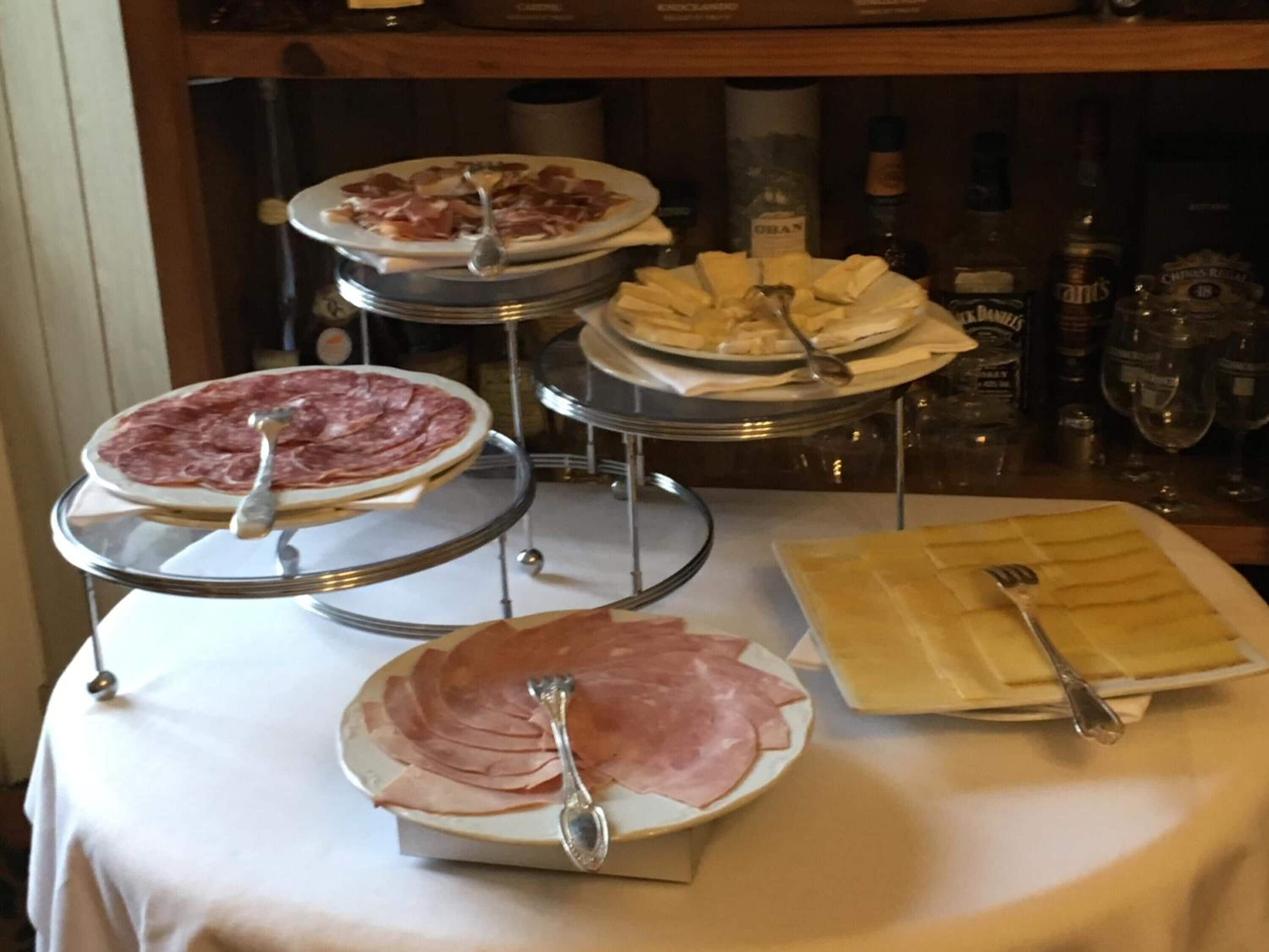 Ein reichhaltiges Buffet mit verschiedenen Speisen, darunter Aufschnitt und Käse, ergänzt durch eine Auswahl an Getränken und Gläsern.