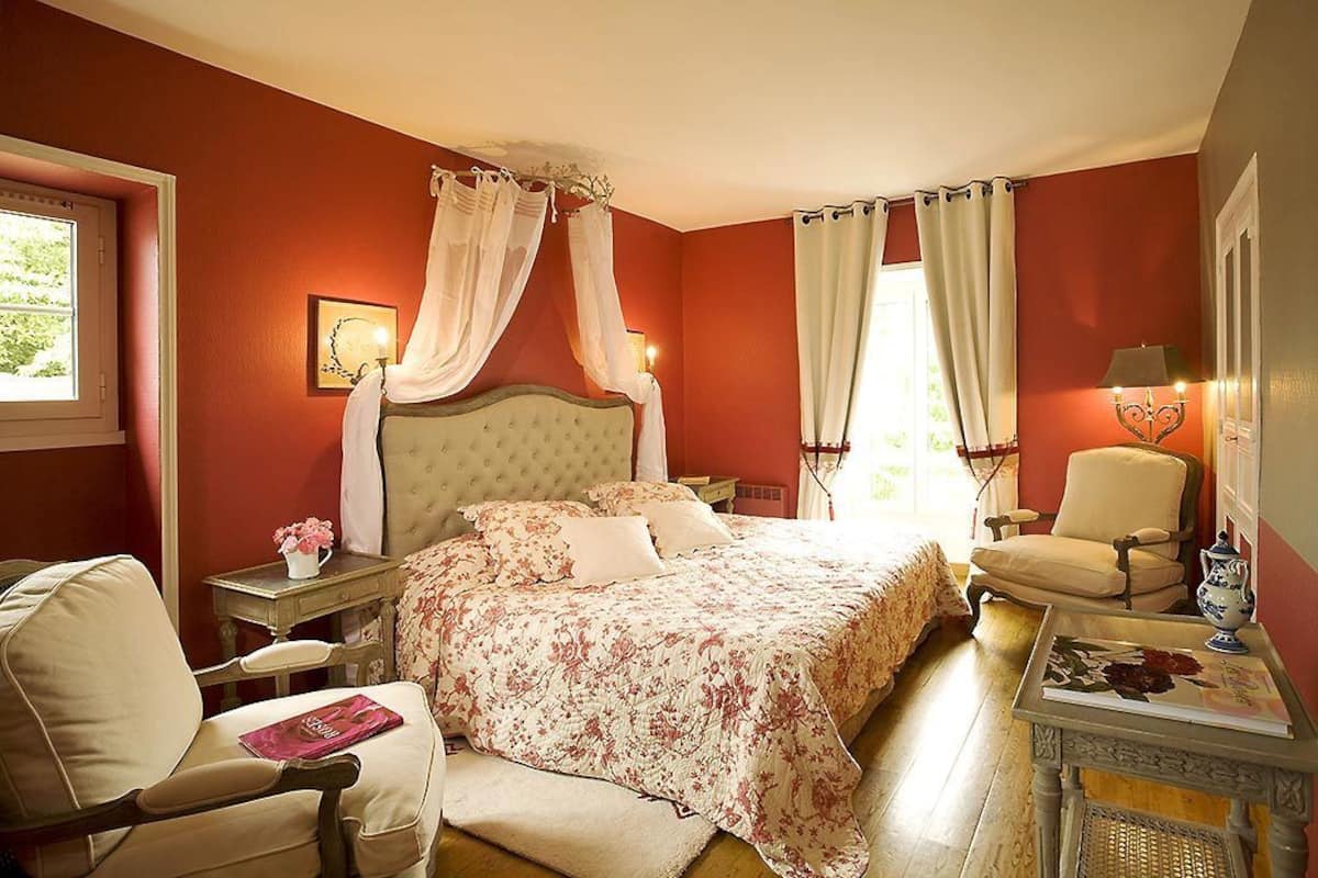 Ein Schlafzimmer mit Bett, Sessel, Tisch und Lampe.