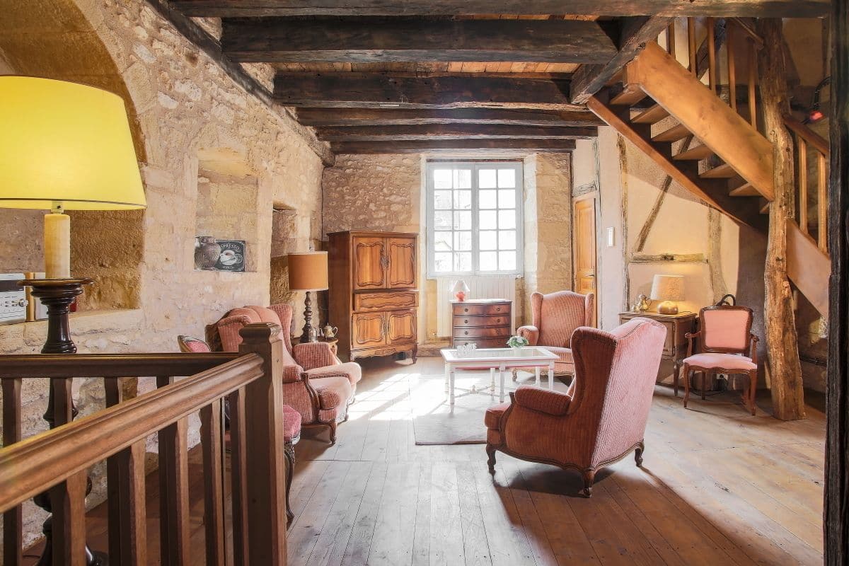 Ein rustikaler Raum mit Holzbalken, einer Treppe und traditionellen Möbeln.