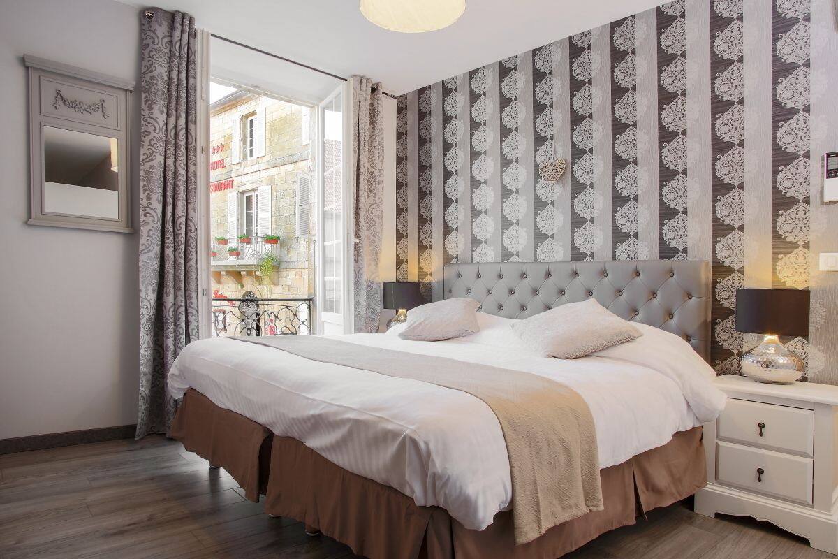 Ein Schlafzimmer mit einem großen Bett, einem Nachttisch, einem Spiegel und Blick auf die Straße.