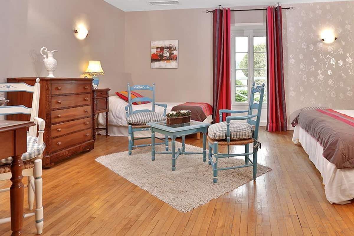 Ein Schlafzimmer mit einem Bett, zwei Stühlen, einer Kommode und einem Nachttisch.