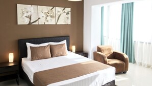 Een moderne hotelkamer met een groot bed, een nachtkastje, een stoel en een raam met gordijnen.