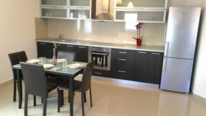 Una cocina moderna con una mesa de comedor preparada para cuatro personas, armarios negros, un refrigerador de acero inoxidable y un horno empotrado.