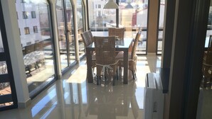 Een eetgedeelte met een tafel en stoelen, grote ramen en uitzicht op buiten.