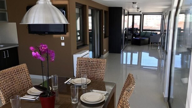 Een moderne eethoek met een glazen tafel, rieten stoelen en een potorchidee.