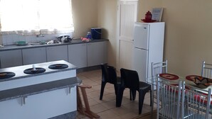 Una cocina con mostrador, pileta y heladera. Hay sillas y una mesa de comedor.