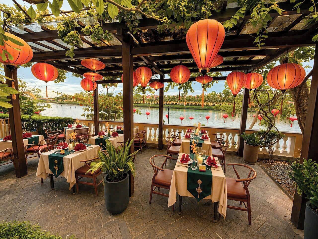 An outdoor dining area with tables set for a meal, overlooking a body of water.