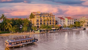 A riverfront hotel with multiple balconies, a dining area, and a boat service. - Little Riverside. A Luxury Hotel & Spa (Da Nang)