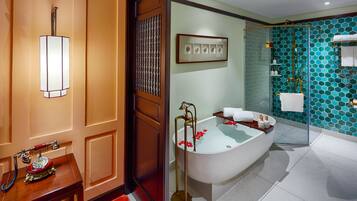 Une salle de bain avec une baignoire sur pieds, un luminaire fixé au mur et un tableau encadré au-dessus de la baignoire.