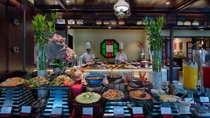 A buffet with various food items and a chef preparing food. - Little Riverside. A Luxury Hotel & Spa (Da Nang)
