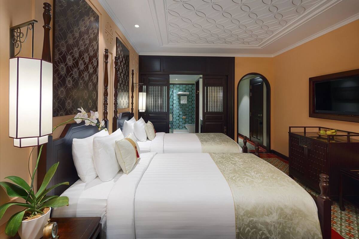 A hotel room with a large bed, a television, a desk, and a mirror.