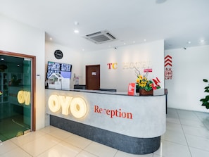 A hotel reception desk with a 'TC HOTEL' sign, a clock, and a reception area with a flower arrangement.