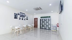 A clean, modern room with white walls, a tiled floor, a flat-screen TV mounted on the wall, a door labeled "PUSH ROOM", and a small shelf with plants. - Super OYO 326 Tc Hotel (Petaling Jaya)