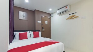 A hotel room with a bed, an air conditioning unit, a coat rack, and a door. - Super OYO 326 Tc Hotel (Petaling Jaya)