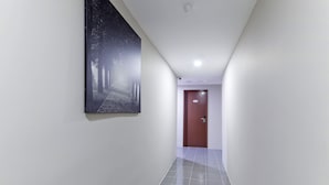 A hallway with a tiled floor, a door at the end, and a large framed picture on the wall. - Super OYO 326 Tc Hotel (Petaling Jaya)