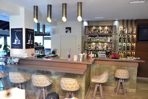 A bar area with a counter, stools, and a well-stocked liquor shelf. - Konaki Hotel & SPA (Aristotelis)