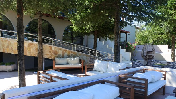 A poolside area with wooden loungers and a stone wall. - Konaki Hotel & SPA (Aristotelis)