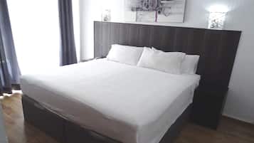 Uma cama bem arrumada com lençóis brancos em um quarto com cabeceira de madeira e um quadro na parede.