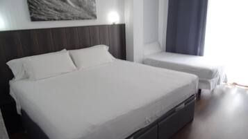 Una habitación de hotel moderna con una cama grande, una cama más pequeña y una mesita de noche.