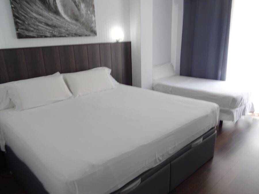 A modern hotel room with a large bed, a smaller bed, and a nightstand.