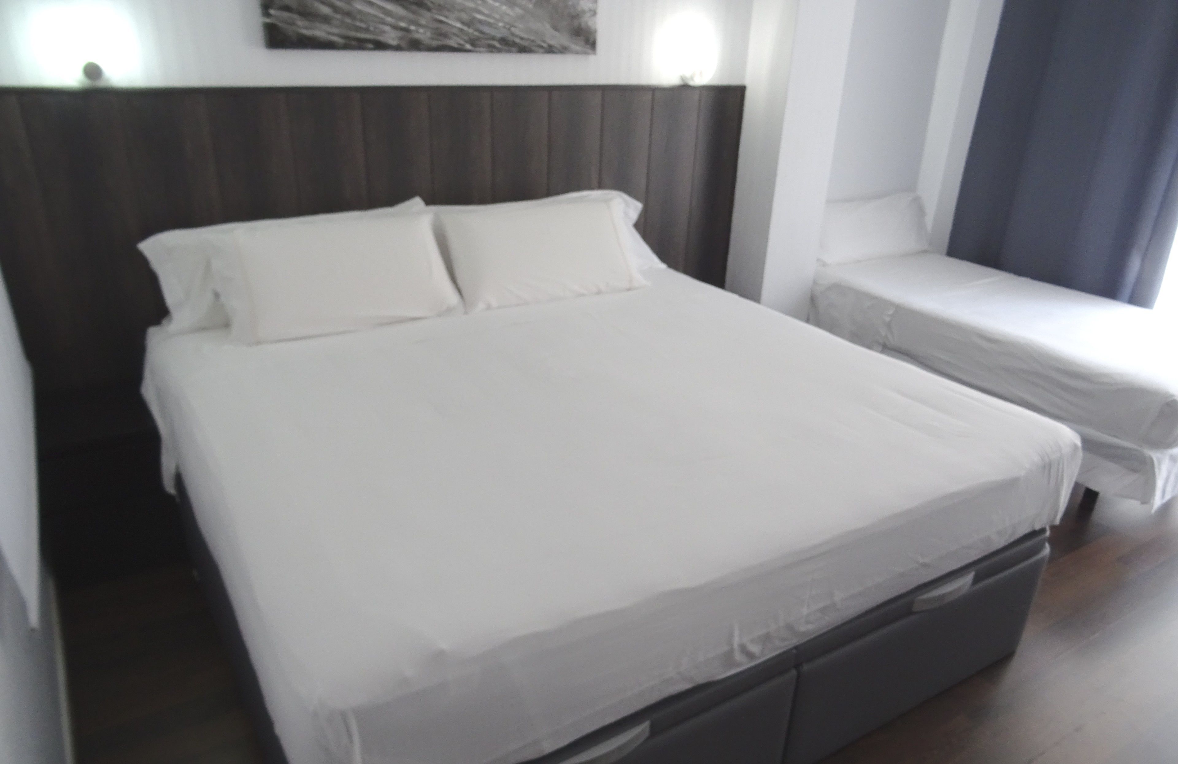 Una habitación de hotel con una cama grande, una mesita de noche y una ventana con cortinas.