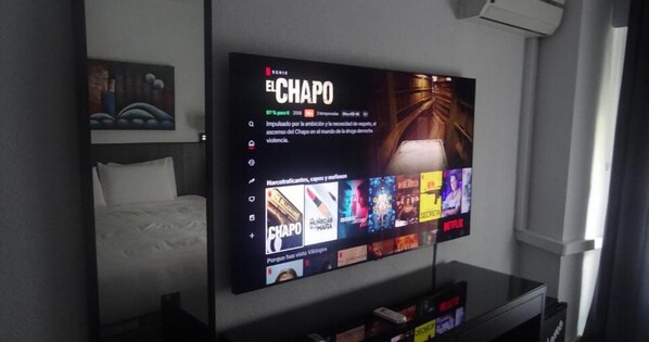 A flat-screen TV mounted on a wall displaying the Netflix series 'El Chapo'.