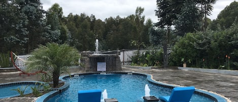 Una piscina al aire libre, sombrillas, sillones reclinables de piscina