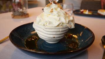 A dessert with whipped cream and caramel sauce on a blue plate.