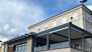 Un hotel con restaurante en la planta baja, que cuenta con una zona de estar al aire libre cubierta y un garaje subterráneo.