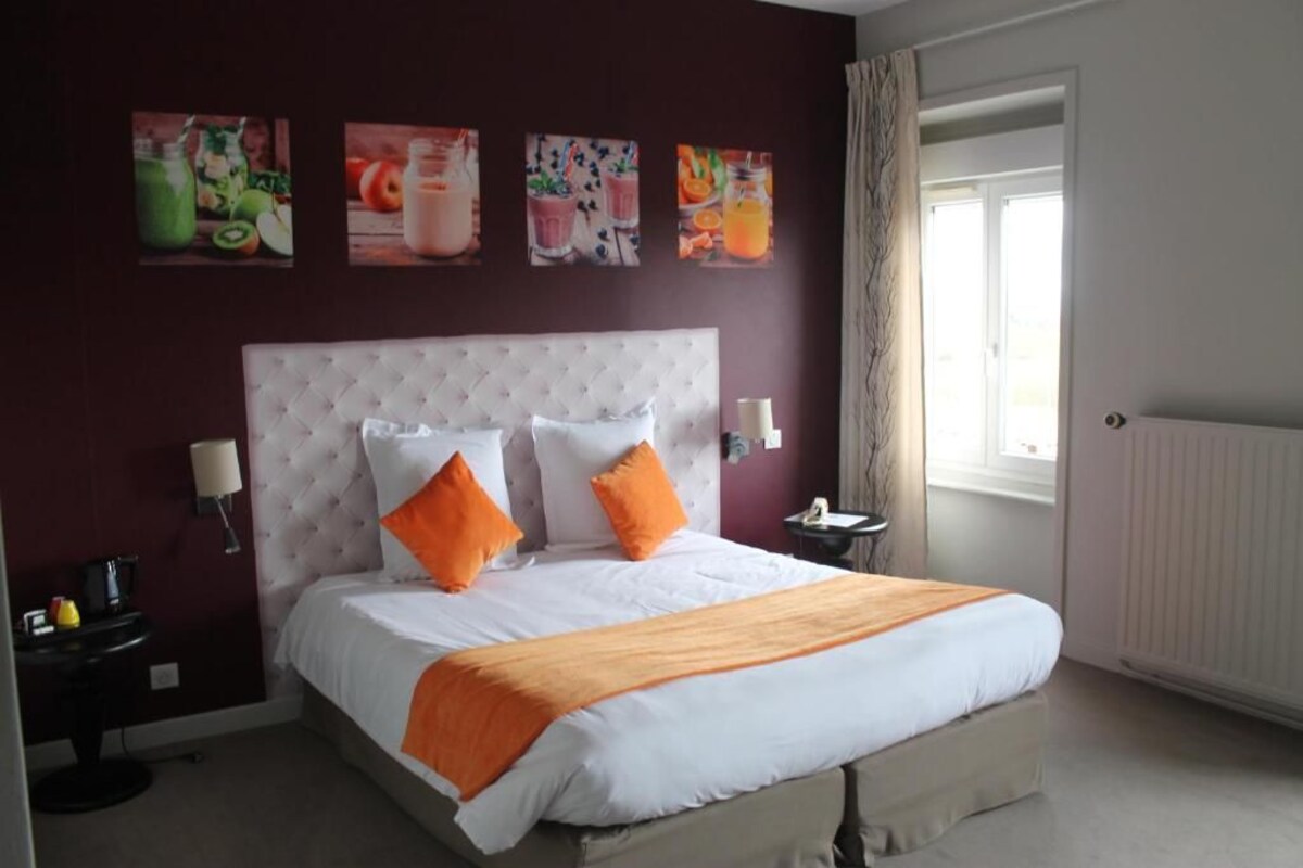 A hotel room with a large bed, a nightstand, a lamp, and a window with curtains.