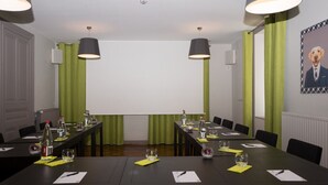 Un salón de conferencias con una larga mesa, sillas y una pantalla para proyector.