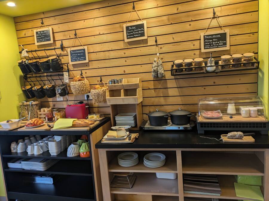 Un comptoir de café avec un revêtement mural en bois, des paniers suspendus, des bocaux et une variété de produits de boulangerie exposés.