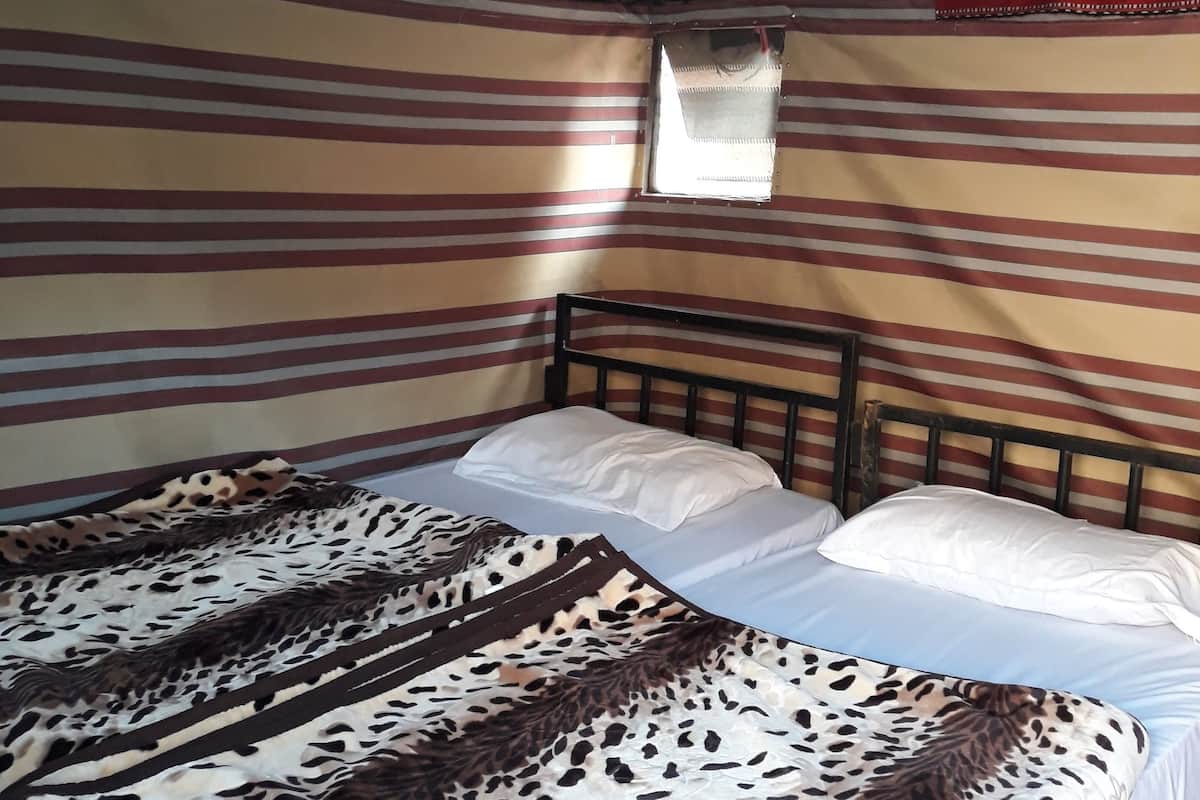 Un lit simple avec une couvre-lit à motifs, une fenêtre donnant sur un paysage agréable et un mur à rayures.
