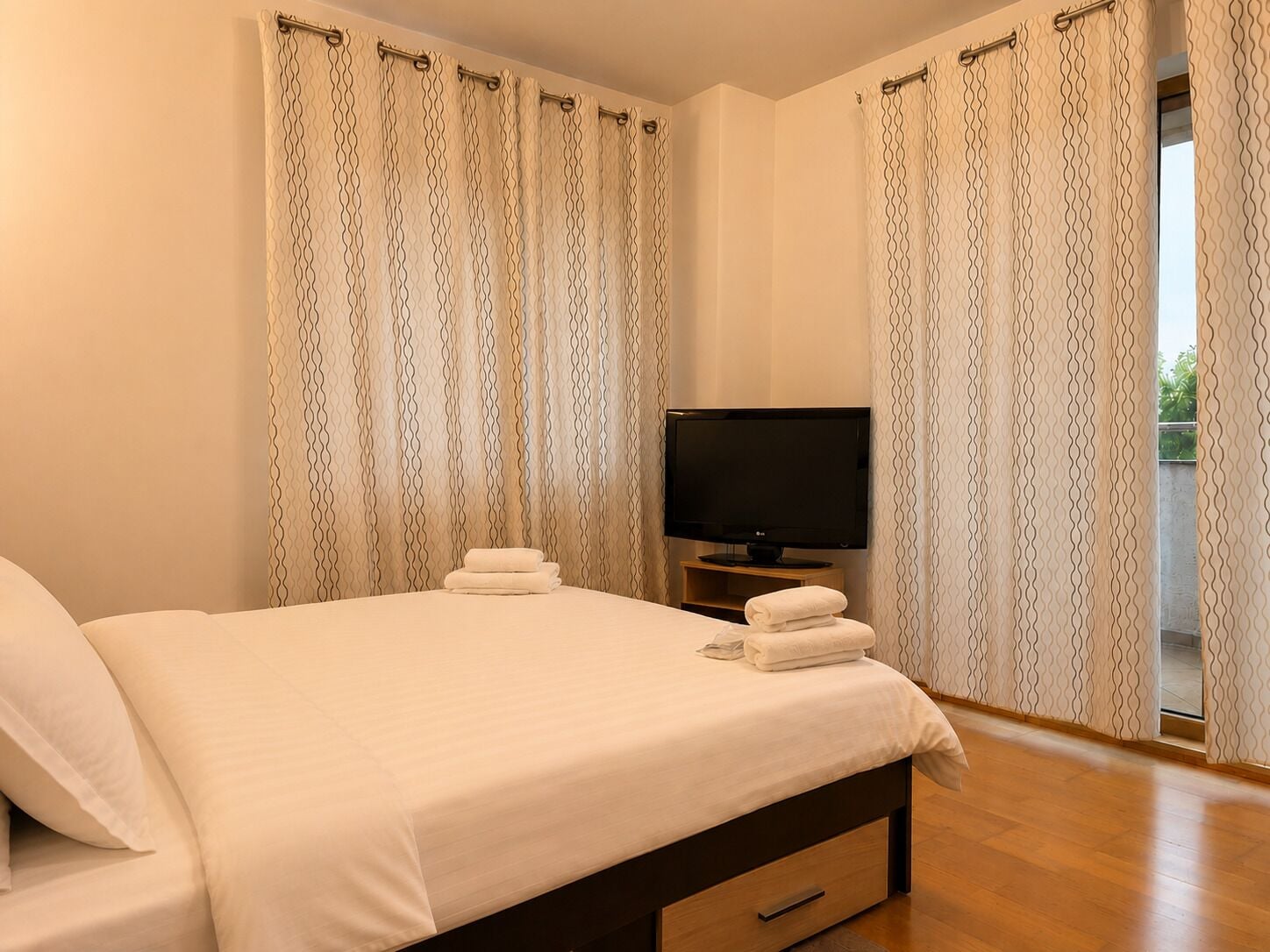 A hotel room with a bed, a television, and curtains.
