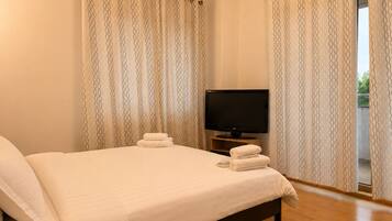 A hotel room with a bed, a television, and curtains.