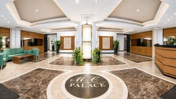 Un vestíbulo de hotel con mostrador de recepción, zona de estar y un elemento decorativo central.
