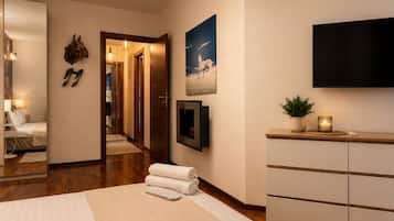 Una habitación de hotel con una cama, un televisor, una planta y un cuadro en la pared.