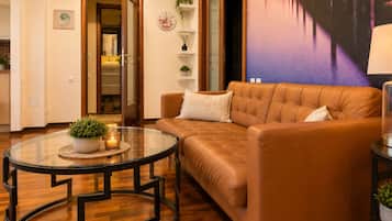 A living room with a brown leather sofa, a glass coffee table with a plant, and a wall clock.